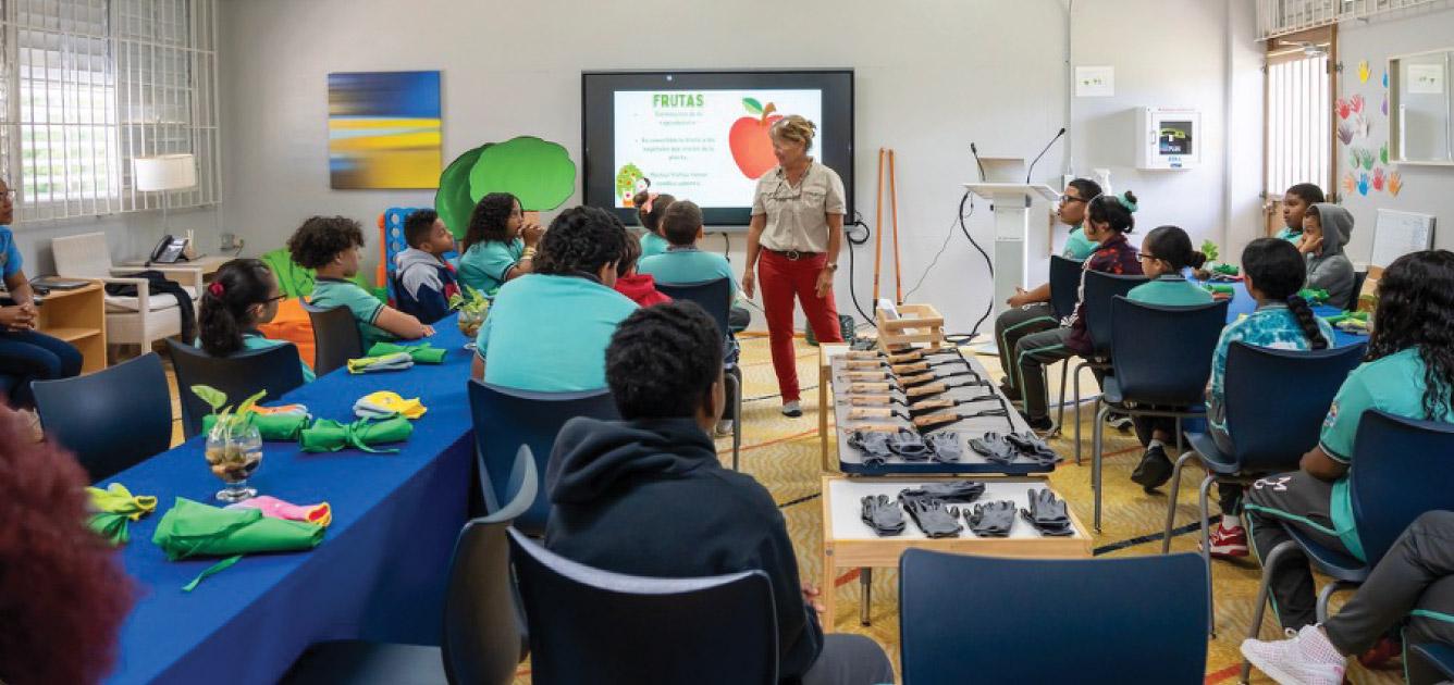 a photo of a group of students being shown a presentation in a room with gardening equipment